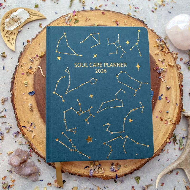Soul Care Planner 2026 with star constellation design on a wooden surface with decorative elements.