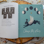 Open book with astrological design and text on a textured surface