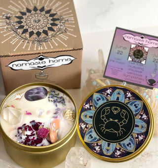 The Cancer Crystal Candle opened with the lid to the right of it. The packaging of the Cancer Crystal Candle is behind the candle next to a card.