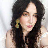 Woman with long dark hair wearing large earrings against a white background
