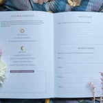 Open book with celestial and flowers on a textured surface