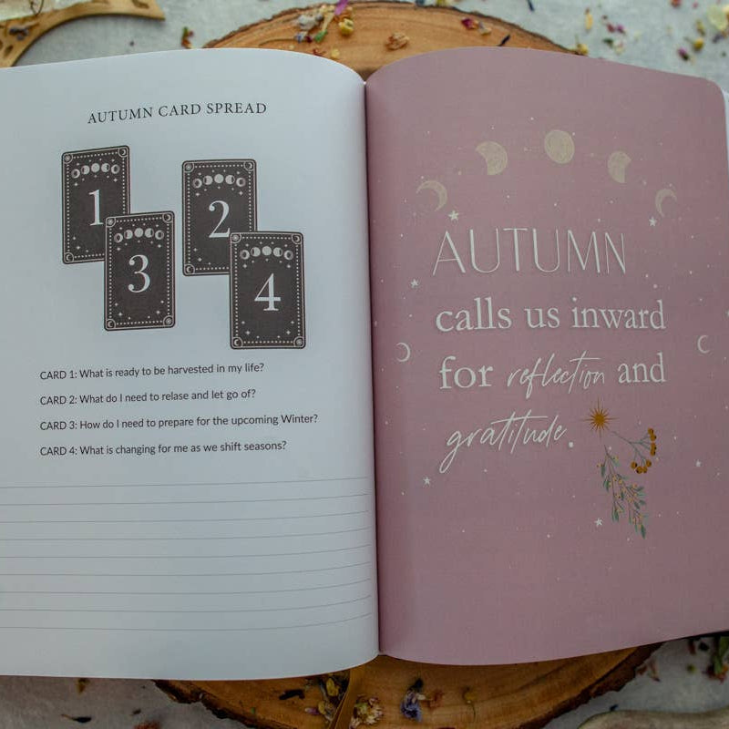 Open book with 'Autumn' theme and card spread on a decorative surface