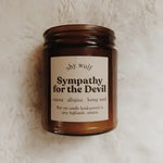 The Sympathy for the Devil candle on a white fluffy surface.