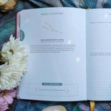 Open book with celestial design on a decorative background with flowers