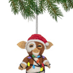 Felt ornament of a character wrapped in Christmas lights hanging from a tree branch.