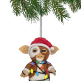 Felt ornament of a character wrapped in Christmas lights hanging from a tree branch.