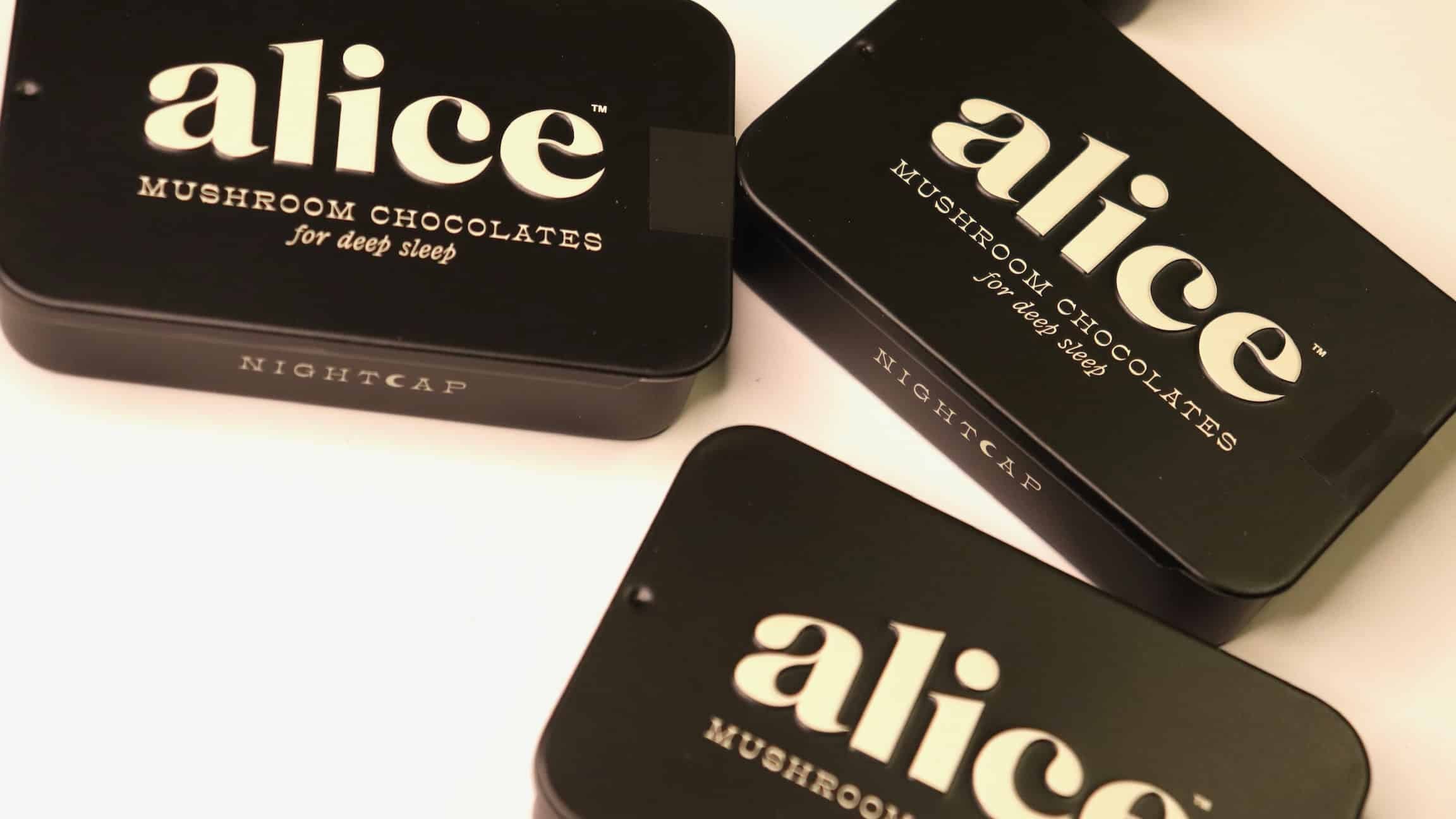 Three black boxes of 'alice' mushroom chocolates on a white background