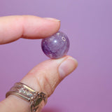 hand holding an amethyst crystal marble