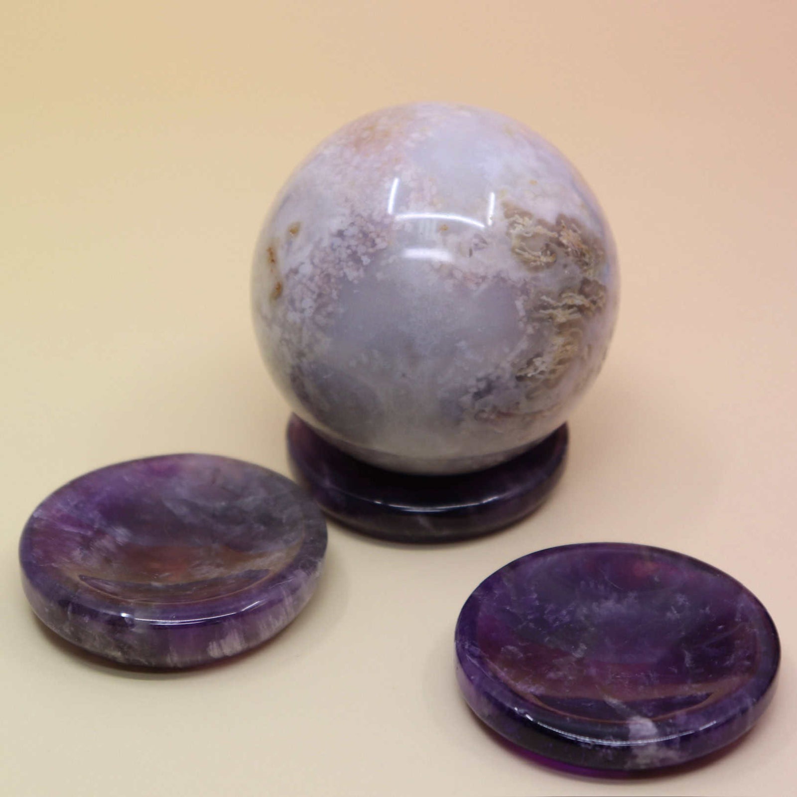 Crystal ball with two purple amethyst stone coasters on a beige background