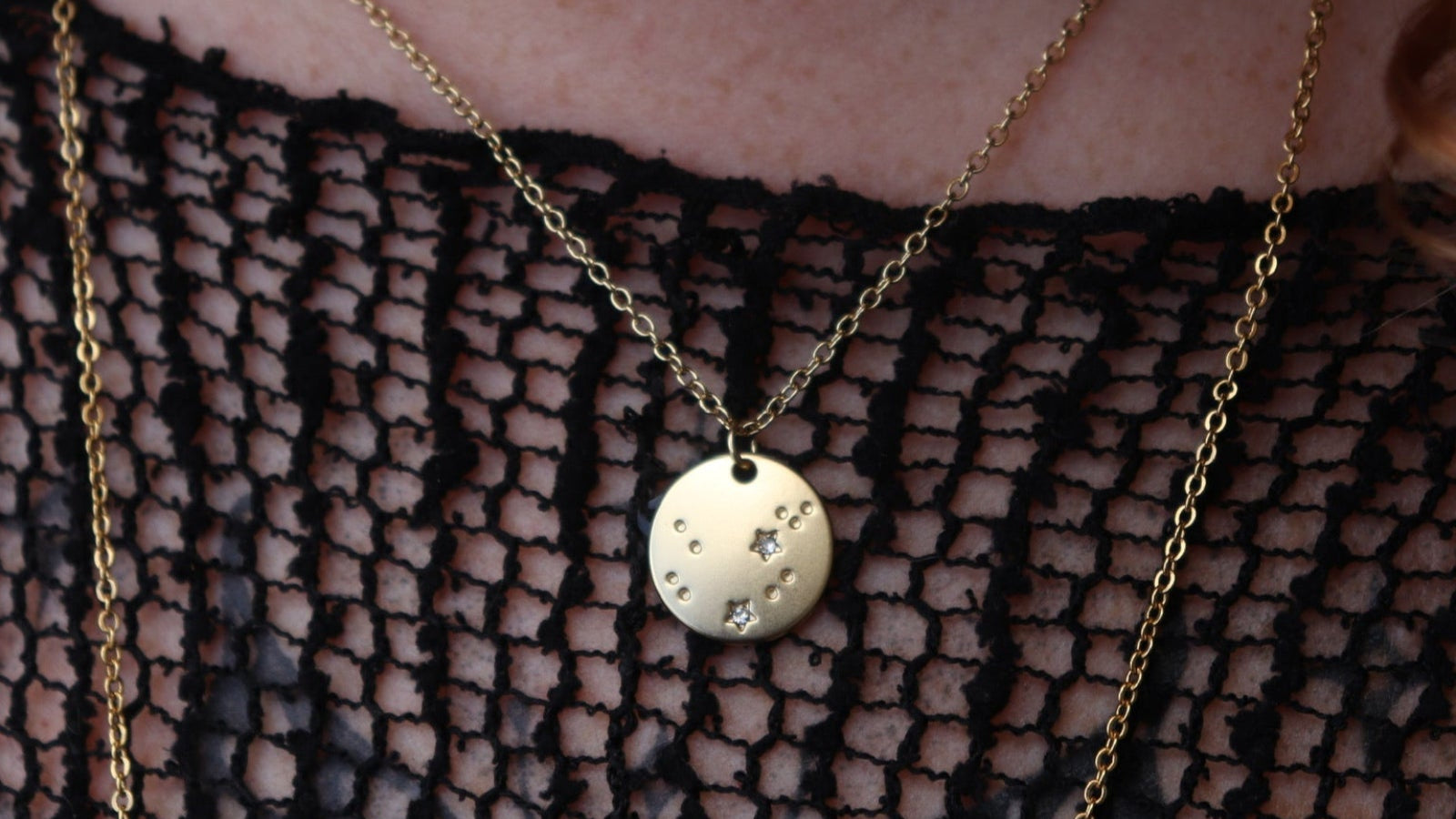 Someone wearing the Aquarius 14k Gold Dipped Nickel-Free Zodiac Necklace with a black net top.