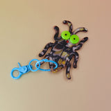 Flat lay of bug keychain with neon eyes and blue clip