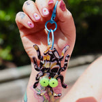 Hand holding thick and juicy bug keychain with pink flower nails