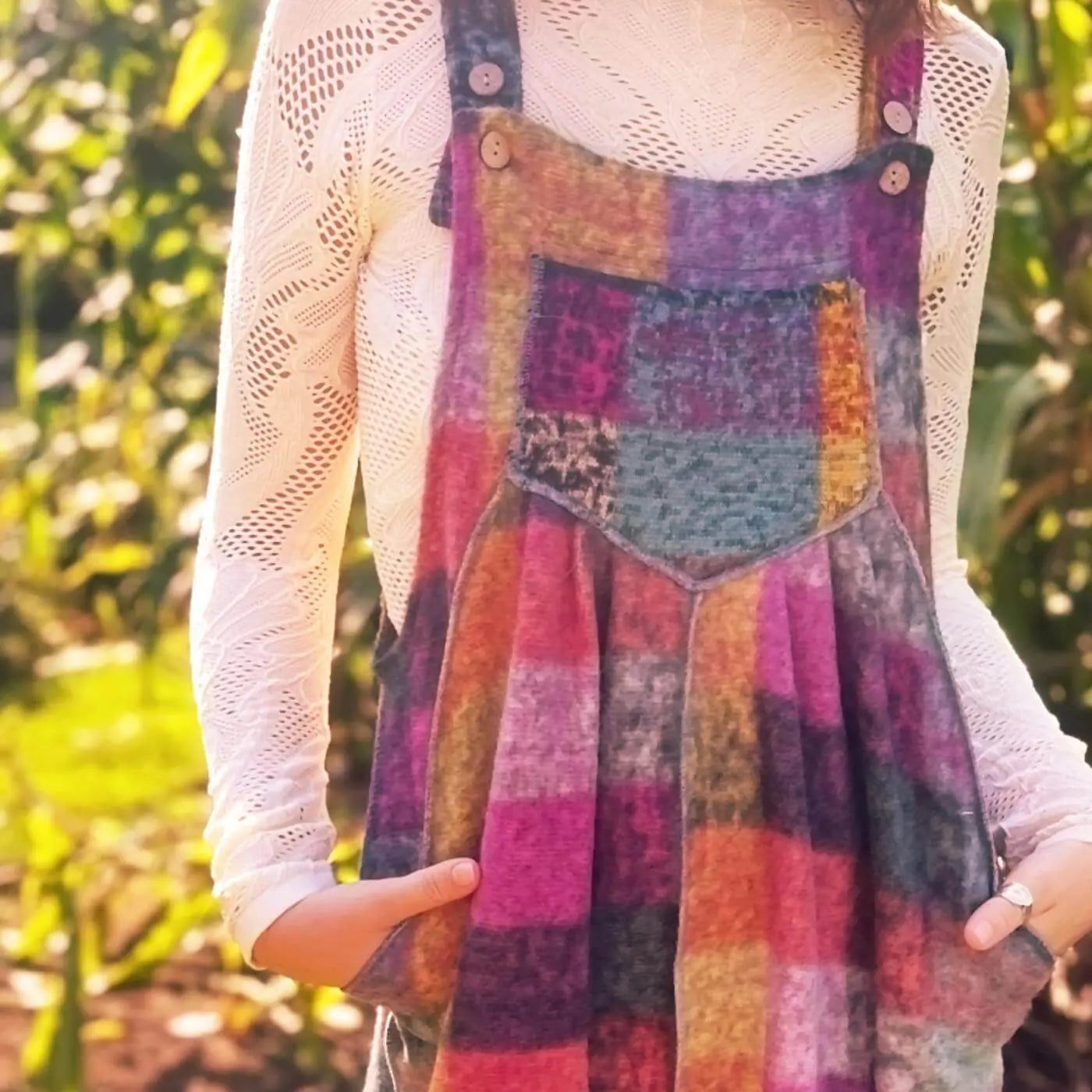 Person wearing a colorful patchwork dress with a blurred natural background