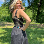 Close-up of striped knit scoop neckline bodice paired with black skirt as woman raises her arms toward the sun.