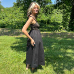 side view of woman posing in a sleeveless ribbed knit bodice dress with a flowing black skirt.