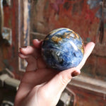 Polished Blue Kyanite crystal sphere in hand for energy alignment
