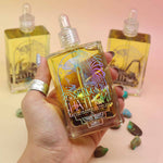 hand holiding a bottle of essence of hathor blue lotus oil with 2 bottles in the background