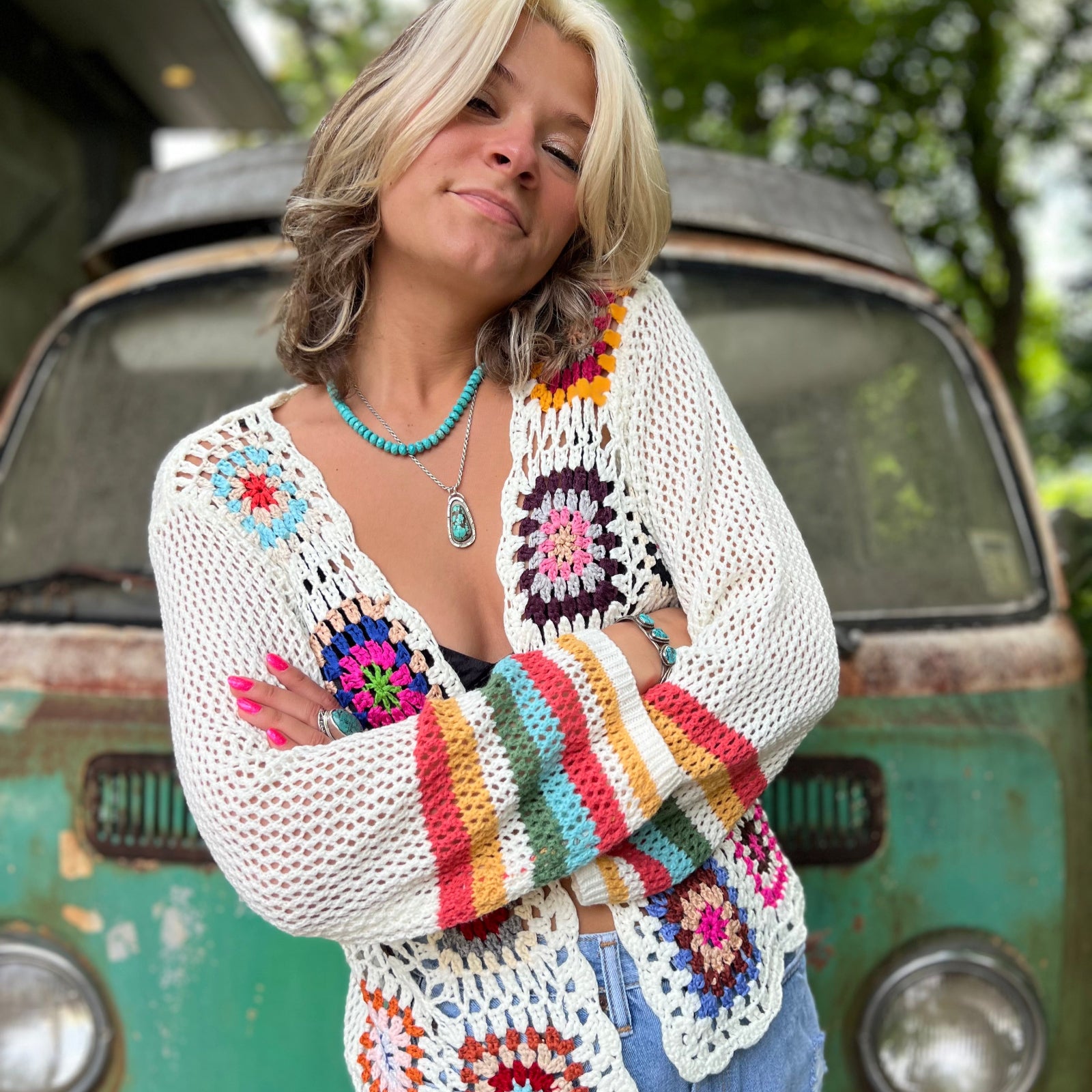 girl wearing a rainbow crochet cardigan in front of vw bus