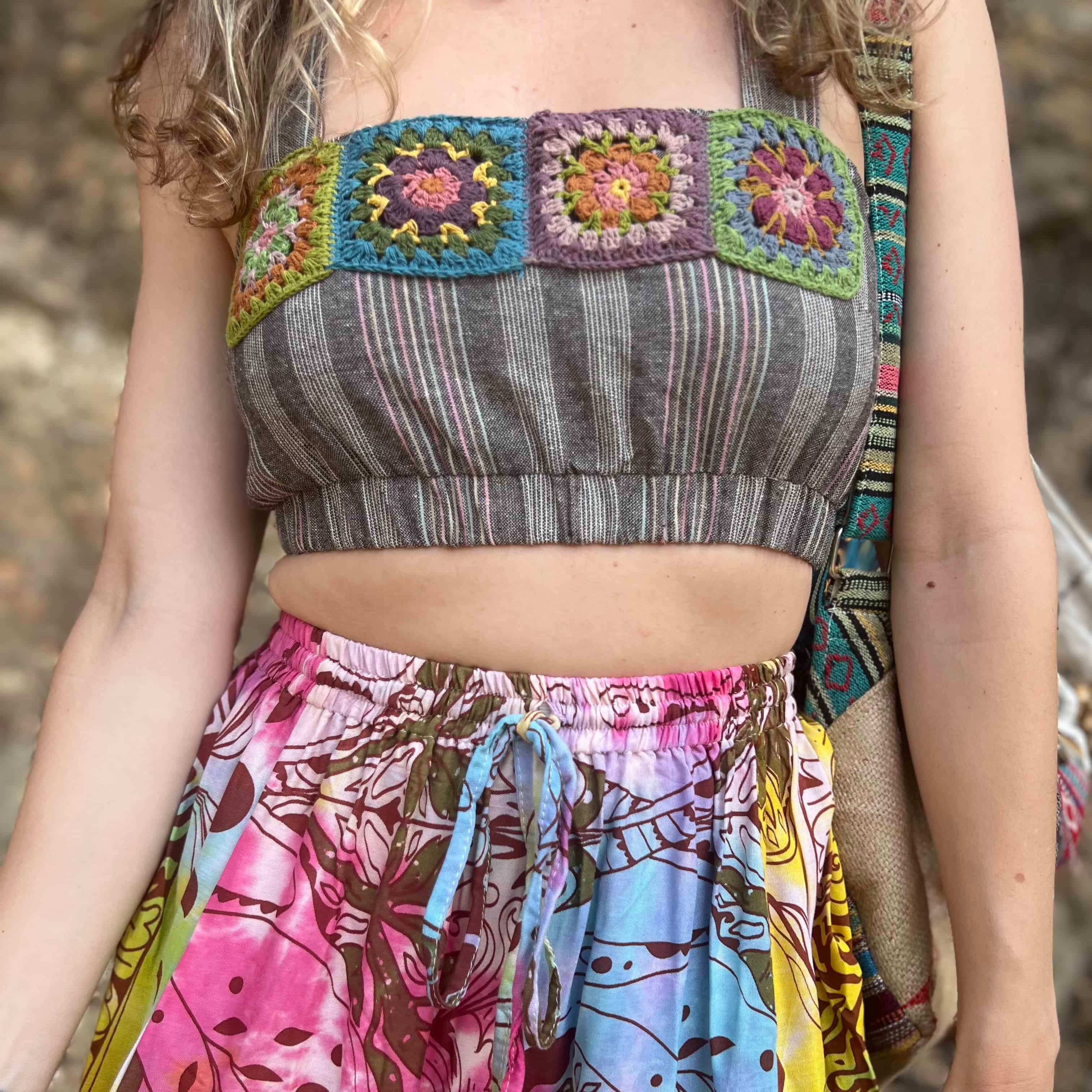 Person wearing a colorful patterned top and skirt with a natural background