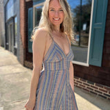 model wearing striped sundress on sidewalk in front of building