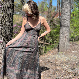 striped dress with models head turned to the side holding the dress up in front of tree stumps