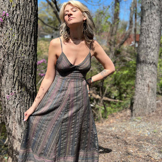girl wearing striped sundress looking up to sun with trees in background