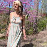 teal striped dress on model walking in front of pink trees in woods