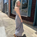 side view of model wearing striped sundress on sidewalk in front of office building