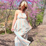 teal striped sundress on modeal with white and black striped hair in front of woods with pink trees