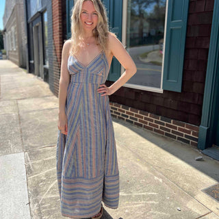 front view of model wearing blue striped sundress on sidewalk with sun shining on her