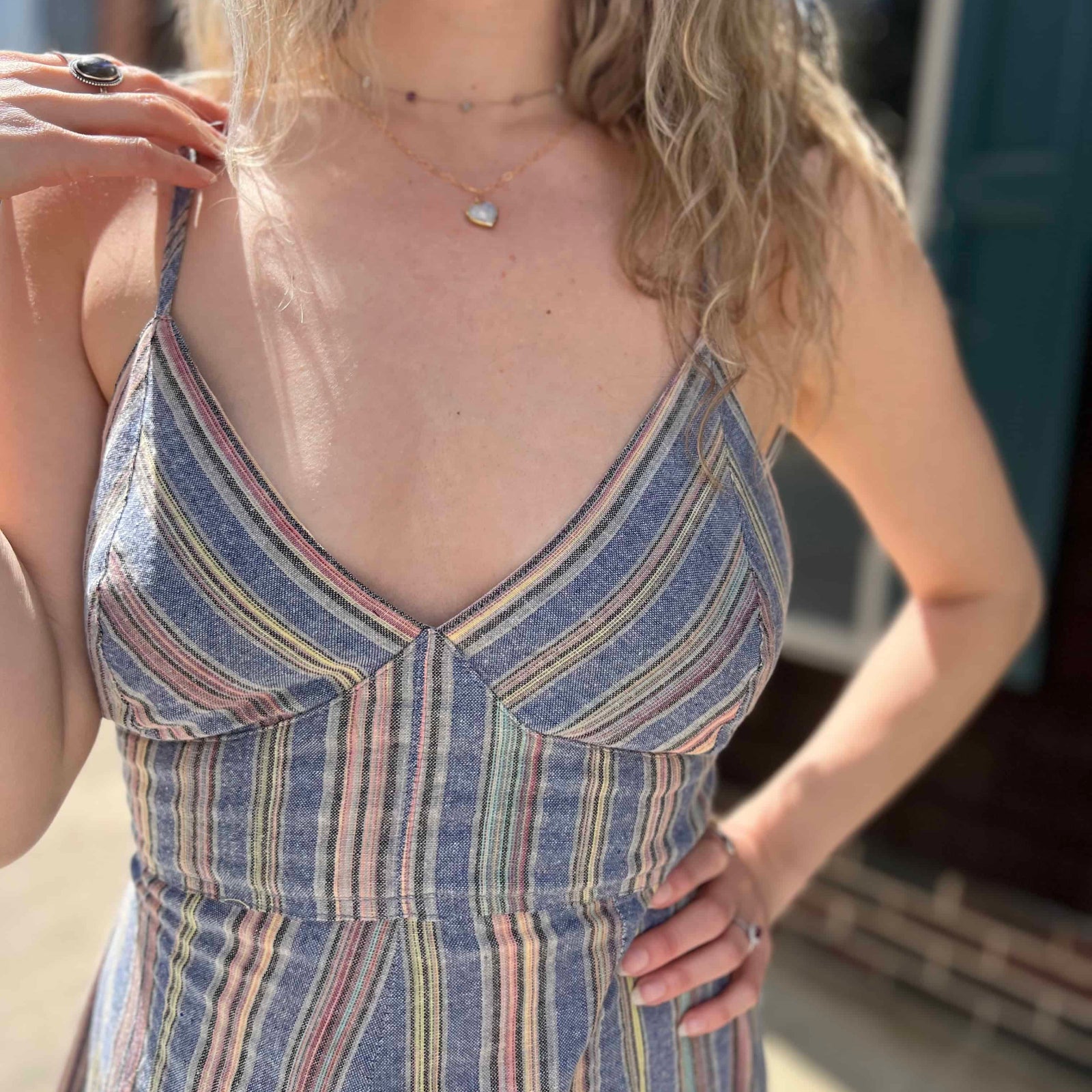 close up view of top of blue striped sundress with hand holding shoulder strap
