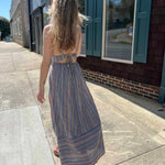 back view of striped sundress on model wearing it walking down sidewalk