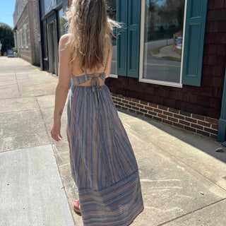 back view of striped sundress on model wearing it walking down sidewalk