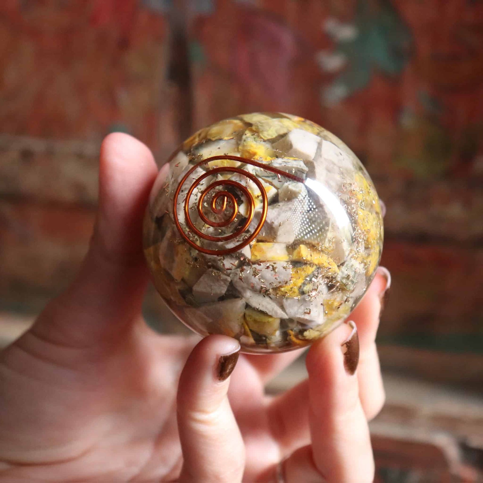 Crystal ball with spiral design held in a hand against a blurred background