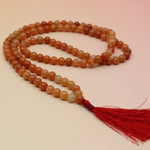 Carnelian 108 Mala Necklace on pink and orange background