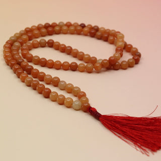 Carnelian 108 Mala Necklace on pink and orange background