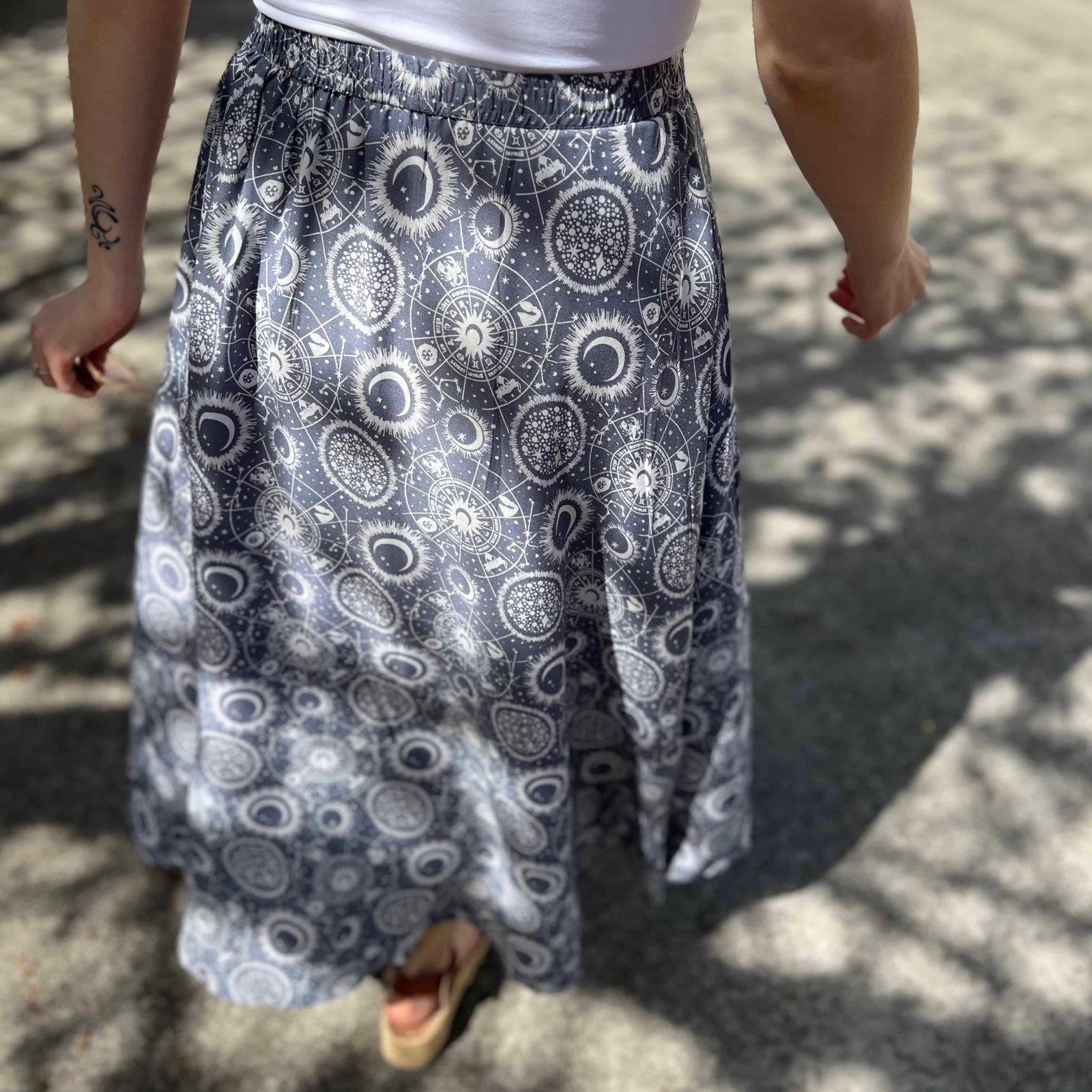 Woman wearing celestial print circle skirt with mandala and moon design view from back of skirt