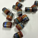 Multiple layered chakra cylinder tumbled stones on a white background, each featuring stacked colorful crystal layers