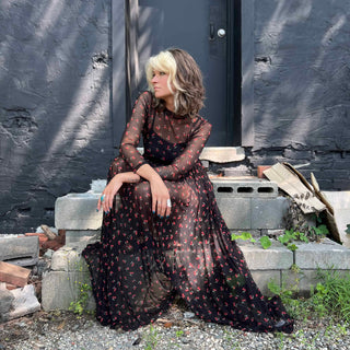 Close-up of the cherry mesh dress as the woman sits, highlighting the print and sheer fabric.