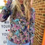 Model running hand through hair in colorful long sleeve high neck fantasy top