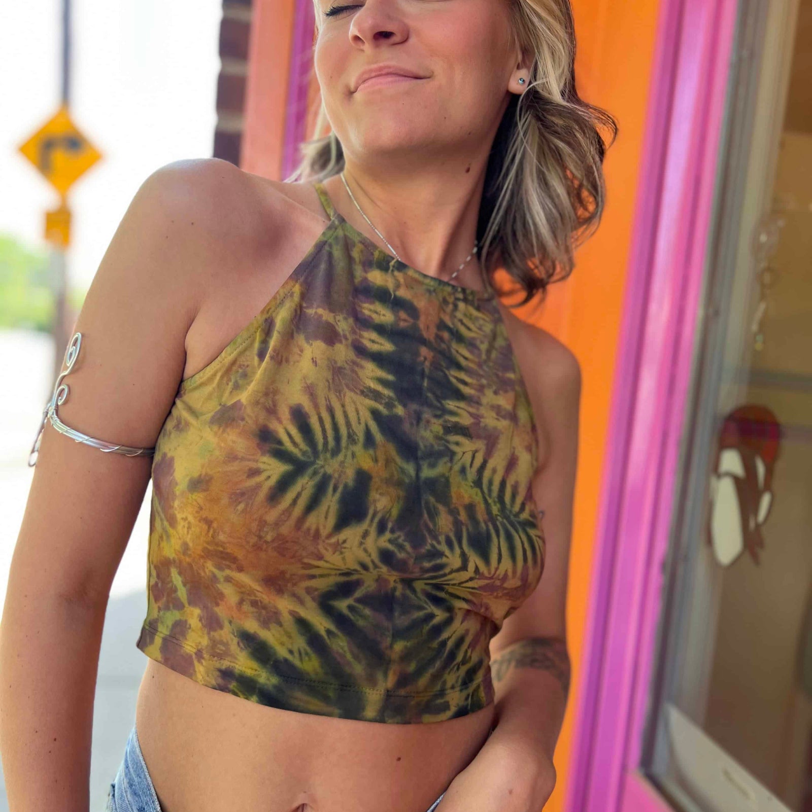 Model wearing green and amber crystal tie-dye crop top with halter neck front view looking up at models face