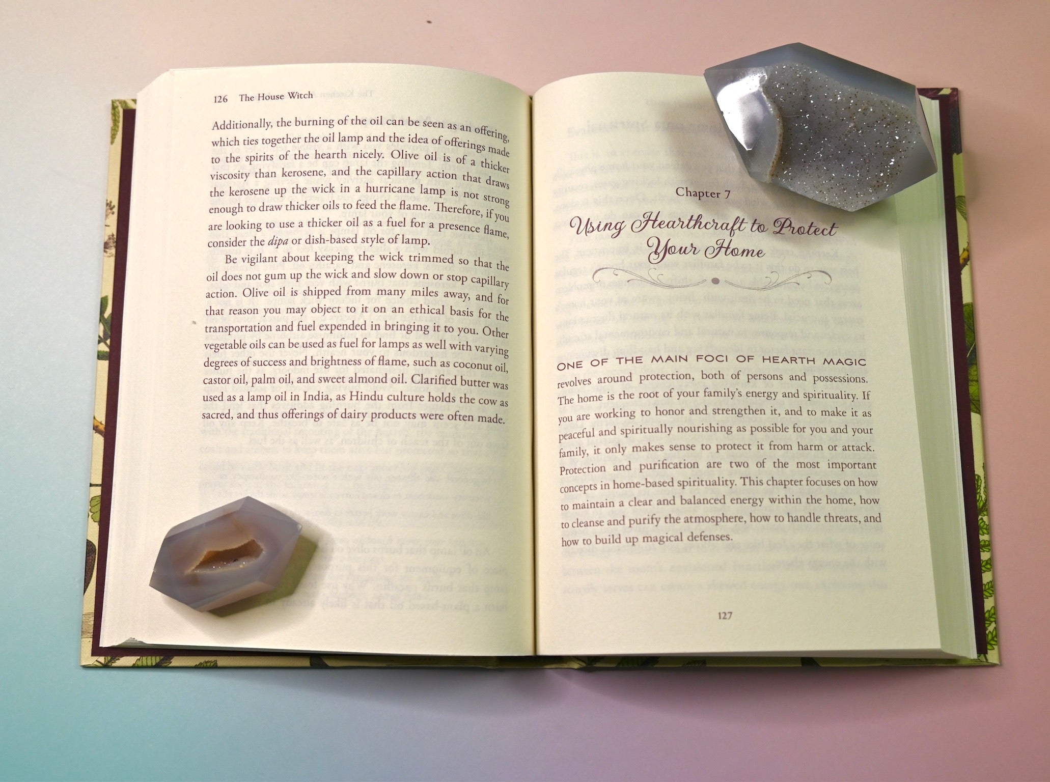 "The House Witch" book on a pink and blue background, showing off its pages.