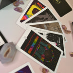 The contents of the Rainbow Brainskull Oracle Deck on a pink and blue background.