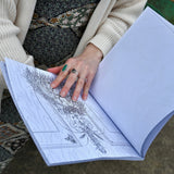 Someone holding the The "Green Witch's Coloring Book", showing off a page.