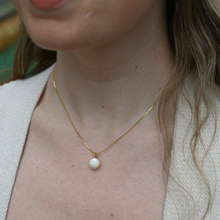 An up-close image of someone wearing the Dainty Vintage Pearl Drop Necklace.