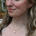 An up-close image of someone wearing the Dainty Vintage Pearl Drop Necklace.