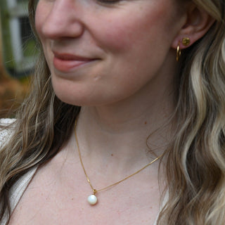 An up-close image of someone wearing the Dainty Vintage Pearl Drop Necklace.