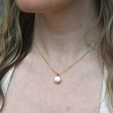 An up-close image of someone wearing the Dainty Vintage Pearl Drop Necklace.