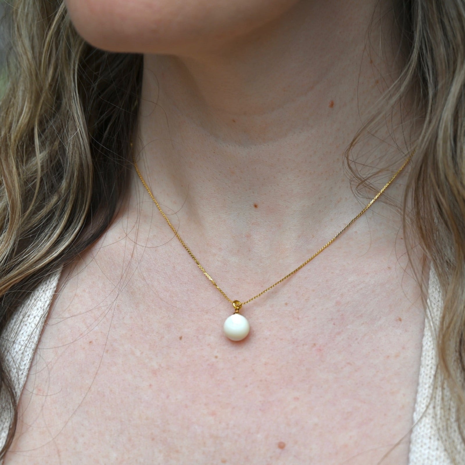 An up-close image of someone wearing the Dainty Vintage Pearl Drop Necklace.