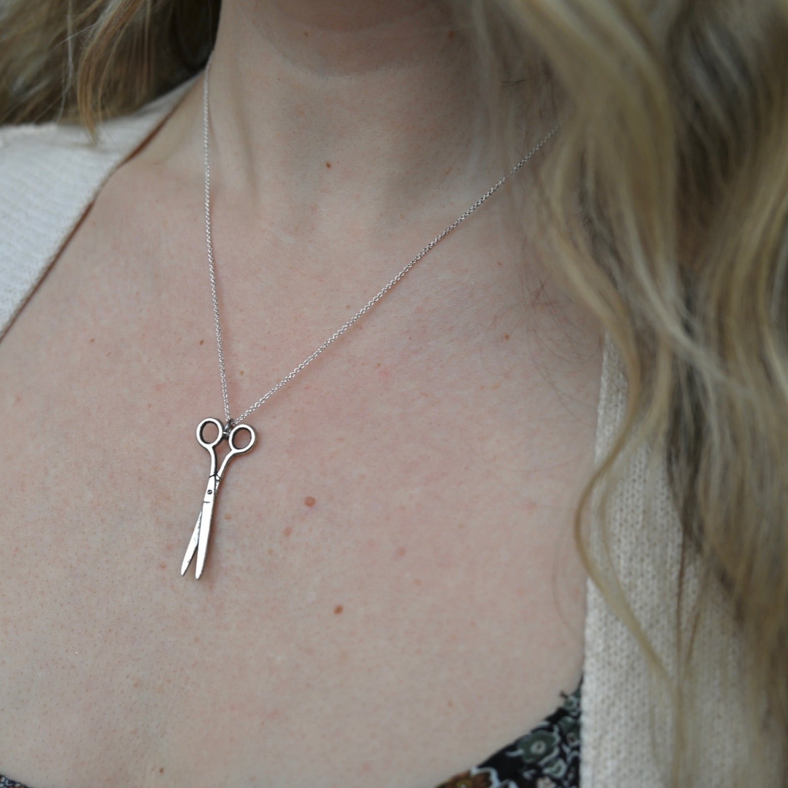 An up-close image of someone wearing the Vintage Silver Scissors Charm Necklace.